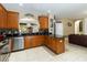 Kitchen features stainless steel appliances, wood cabinetry, and access to a living room with a brown leather couch at 2509 Archfeld Blvd, Kissimmee, FL 34746