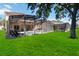 Sprawling backyard with screened in pool, lounge chairs, and outdoor kitchen at 2509 Archfeld Blvd, Kissimmee, FL 34746