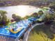This aerial view shows a community waterpark, splashpad, and waterslide with a lake in the background at 2509 Archfeld Blvd, Kissimmee, FL 34746