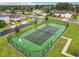 View of tennis court and basketball hoop surrounded by a fence, with neighborhood homes in the background at 254 Andalusia Loop, Davenport, FL 33837