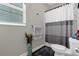 Cozy bathroom with a toilet, gray striped shower curtain, and a window with blinds at 2613 Camden Park Loop, Davenport, FL 33837