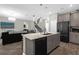 Open kitchen featuring island with sink, seating, stainless appliances, and adjacent living area with modern decor at 2613 Camden Park Loop, Davenport, FL 33837