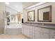 Well-lit bathroom showcasing a soaking tub and granite countertop vanity with dual mirrors at 26901 Racquet Cir, Leesburg, FL 34748