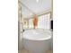 Bright main bathroom with garden tub beneath a window, tile surround, and adjacent shower at 26901 Racquet Cir, Leesburg, FL 34748