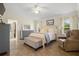 Well-lit main bedroom with large bed, ceiling fan, tile floors and ensuite bathroom at 26901 Racquet Cir, Leesburg, FL 34748