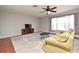 Bright living room features a ceiling fan, television, and natural light from a large window at 297 Sky Valley St, Clermont, FL 34711