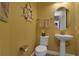 Nautical-themed powder room features a pedestal sink, toilet, and decorative ship wheel accent at 3083 Key Lime Loop, Kissimmee, FL 34747