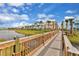 Bridge over pond with colorful Margaritaville condos, green lawn, palm trees, and blue sky at 3083 Key Lime Loop, Kissimmee, FL 34747