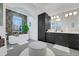 Modern bathroom with a freestanding tub, marble accent wall, black cabinetry, and contemporary lighting at 3382 Fernlake Pl, Longwood, FL 32779