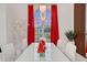 Bright dining room featuring elegant chandelier, white table, and red curtains framing the window view at 3382 Fernlake Pl, Longwood, FL 32779