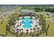 Aerial view of community pool with palm trees, lounge chairs, and a clubhouse, enhancing the neighborhood's appeal at 4307 Pebbles Throw Dr, Kissimmee, FL 34746