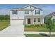 Charming two-story home with light blue siding, a two-car garage, and a manicured front lawn at 4307 Pebbles Throw Dr, Kissimmee, FL 34746
