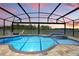 Sparkling pool with a screened enclosure overlooking a serene lake and colorful sunset at 4307 Pebbles Throw Dr, Kissimmee, FL 34746