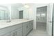 A full bathroom view with grey cabinets, double vanity, grey walls, and white trim at 4787 Guinep Ln, Kissimmee, FL 34758