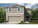 Charming two-story home featuring light beige siding, a two-car garage, and well-maintained landscaping at 4787 Guinep Ln, Kissimmee, FL 34758