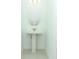 A pristine powder room with a pedestal sink, toilet, and decorative mirror at 4787 Guinep Ln, Kissimmee, FL 34758