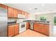Modern kitchen with stainless steel appliances, wood cabinets, and a breakfast bar open to the living area at 5004 Ashford Falls Ln, Oviedo, FL 32765