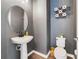 Stylish powder room with a pedestal sink, modern fixtures, and decorative accents at 5660 Oak Knoll Dr, St Cloud, FL 34771