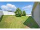 Large grassy backyard featuring mature trees, a white fence, and home exterior at 5829 Valentino Way, Lakeland, FL 33812