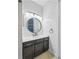 Modern bathroom featuring white subway tile, dark vanity, and an elegant round mirror at 5829 Valentino Way, Lakeland, FL 33812