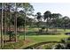 Picturesque golf course with tall trees, manicured landscaping, and a glimpse of water features in the distance at 605 Ensenada Dr, Orlando, FL 32825