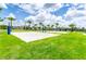 Sand volleyball court on a sunny day surrounded by palm trees and lush green lawns at 7759 Westland Dr, Kissimmee, FL 34747