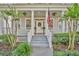 Inviting front porch with classic columns, an American flag, and lush landscaping at 821 Veranda Pl, Celebration, FL 34747