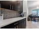 Elegant dry bar featuring dark cabinets, light countertops, and a stylish backsplash at 8643 Coventry Park Way, Windermere, FL 34786