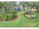 Landscaped front yard with mature trees and shrubs surrounding a charming home with a front porch at 89 Pine Forest Ln, Haines City, FL 33844