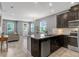 Modern kitchen featuring stainless steel appliances, dark cabinets, and granite countertops with a view to the Gathering room at 9433 Randal Park Blvd, Orlando, FL 32832