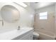 Bright bathroom with white vanity, round mirror, tub-shower combo, and a window at 25929 Newcombe Cir, Leesburg, FL 34748