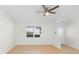 Bright and airy living room with light wood floors, ceiling fan, and large window at 25929 Newcombe Cir, Leesburg, FL 34748
