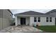 View of the home's back exterior with a neutral color, small patio, sliding glass doors, and a small grassy area at 669 Big Pine Ave, Minneola, FL 34715