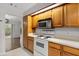 Kitchen with white appliances, wood cabinets, and view to outside patio at 503 Moree Loop, Winter Springs, FL 32708