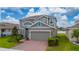 Charming two-story home showcasing a gray exterior, manicured landscaping, and a brick driveway leading to a garage at 1317 Yorkdale Rd, Davenport, FL 33837