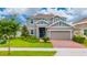 Charming two-story home featuring a well-manicured lawn, brick driveway, and a welcoming blue front door at 1317 Yorkdale Rd, Davenport, FL 33837