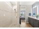 Modern bathroom with gray vanity, a double sink, and walk-in shower with beige tiling at 6137 Blue Pond Way, St Cloud, FL 34771
