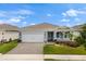 Attractive single-story home featuring a brick-paved driveway, lush landscaping, and light blue siding at 6137 Blue Pond Way, St Cloud, FL 34771