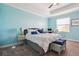 A well-lit bedroom with light blue walls, a ceiling fan, a bed, and a window for natural light at 1350 Royal St George Blvd, Davenport, FL 33896