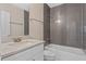Modern bathroom featuring gray tiling in shower, granite vanity top, and updated fixtures at 1440 Lake Shore Dr, Casselberry, FL 32707