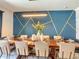 Dining area features a long wooden table, modern light fixture, blue accent wall, and seating for ten at 1491 Rolling Fairway Dr, Davenport, FL 33896