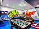 Spacious game room with colorful murals, foosball table, air hockey, and seating, perfect for Gathering fun and entertainment at 1491 Rolling Fairway Dr, Davenport, FL 33896