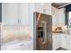 Bright kitchen features white cabinets, stainless steel refrigerator, herringbone backsplash, and granite countertops at 15148 Willow Ridge Dr, Montverde, FL 34756