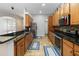 Well-lit kitchen featuring wood cabinets, granite counters, stainless appliances, and tan tile flooring at 18 Cooledge St, Winter Garden, FL 34787