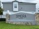 Dimora Park's entrance sign featuring stone accents, grey stucco, manicured lawn, and black lettering at 2025 Claudia Ln # 2025, Kissimmee, FL 34741