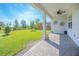 Outdoor patio features a fan and leads to a large green lawn with mature landscaping and blue skies at 2490 Southlawn Ln, Clermont, FL 34714