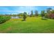 Wide shot of the lush green lawn, mature trees, and a peaceful pond in the backyard at 2490 Southlawn Ln, Clermont, FL 34714