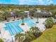 Aerial view of community pool with ample seating, surrounded by palm trees, and next to clubhouse at 2490 Southlawn Ln, Clermont, FL 34714