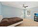 Well lit bedroom featuring carpet, ceiling fan, two windows and neutral blue walls at 318 Osprey Lakes Cir, Chuluota, FL 32766
