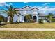 Charming two-story home featuring a blue exterior, arched entryway, and lush landscaping, including mature palm trees at 318 Osprey Lakes Cir, Chuluota, FL 32766